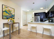 Thumbnail 9 of 35 - A kitchen with a bar and a painting on the wall at Axis at Lakeshore Apartments, Bridgewater, MA