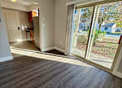 Thumbnail 10 of 18 - a living room with a large window and a door to a kitchen at Hidden Brook Apartment Homes Apartments, New Bedford