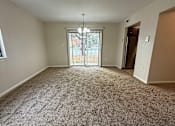 Thumbnail 12 of 18 - an empty living room with carpet and a door to a balcony at Hidden Brook Apartment Homes Apartments, New Bedford, 02740