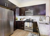 Thumbnail 13 of 35 - A kitchen with a stainless steel refrigerator, microwave, and oven at Axis at Lakeshore Apartments, Massachusetts