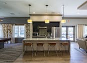 Thumbnail 25 of 35 - A kitchen with a bar and chairs at Axis at Lakeshore Apartments, MA,02324