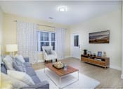 Thumbnail 4 of 35 - A living room with a grey sofa, a wooden coffee table, and a painting on the wall at Axis at Lakeshore Apartments, Bridgewater, Massachusetts