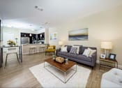 Thumbnail 6 of 35 - A modern living room with a grey couch, a coffee table, and a painting on the wall at Axis at Lakeshore Apartments, Massachusetts