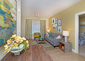 Thumbnail 10 of 35 - A living room with a grey couch, a coffee table, and a painting on the wall at Axis at Lakeshore Apartments, MA,02324
