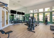 Thumbnail 12 of 28 - A gym with a variety of equipment including treadmills, weights, and exercise machines.