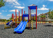 Thumbnail 23 of 28 - A playground with a blue slide and red and yellow play structures.