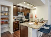 Thumbnail 15 of 28 - A kitchen with a granite countertop and a black chair.
