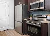 Thumbnail 64 of 85 - A modern kitchen with a stainless steel refrigerator, microwave, and oven.