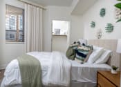 Thumbnail 72 of 85 - A bedroom with a bed covered in a white sheet and a green blanket.