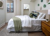 Thumbnail 71 of 85 - A bedroom with a bed covered in a white comforter and a green throw blanket.