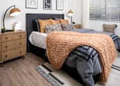 Thumbnail 75 of 85 - A bedroom with a bed covered in a large orange blanket.