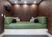 Thumbnail 50 of 85 - A green couch with two pillows sits against a brick wall.