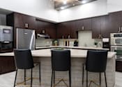 Thumbnail 20 of 85 - A kitchen with a bar area and three black chairs.