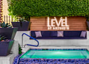 Thumbnail 38 of 85 - A pool with a blue tiled edge and a wooden sign that says "LEVEL" in front of a green wall.