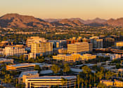 Thumbnail 3 of 85 - A cityscape with buildings and mountains in the background.