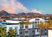 Thumbnail 1 of 72 - A cityscape with buildings and palm trees in the foreground and mountains in the background.