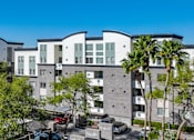 Thumbnail 71 of 72 - A modern apartment complex with a parking lot in front.
