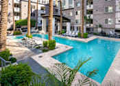 Thumbnail 28 of 72 - A swimming pool surrounded by palm trees and lounge chairs.
