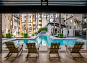 Thumbnail 24 of 72 - A pool with three chairs in front of a building.
