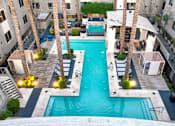 Thumbnail 27 of 72 - A swimming pool surrounded by palm trees and buildings.