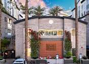 Thumbnail 37 of 72 - A modern building with a brown facade and a sign that reads "Level" is surrounded by palm trees and other greenery.