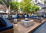 Thumbnail 41 of 72 - A modern outdoor seating area with blue cushions and wooden benches.