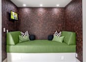 Thumbnail 42 of 72 - A green couch with a pillow and a TV on the wall.
