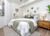 Thumbnail 59 of 72 - A bedroom with a large bed, a nightstand, and a ceiling fan.