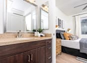 Thumbnail 65 of 72 - A bathroom with a sink, mirror, and a bedroom in the background.