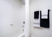Thumbnail 66 of 72 - A white bathroom with a shower and towel rack.