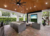 Thumbnail 31 of 38 - A patio with a ceiling fan and a couch.