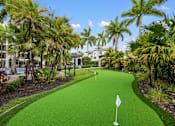 Thumbnail 36 of 38 - A green flag on a golf course surrounded by trees.