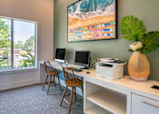 Thumbnail 10 of 29 - A room with a desk, chairs, and a large painting of a beach scene.