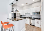 Thumbnail 18 of 49 - a kitchen with white cabinets and black countertops