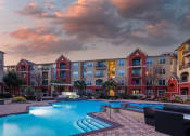 Thumbnail 1 of 54 - a swimming pool at dusk with an apartment building in the background