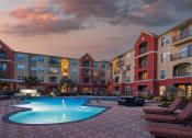 Thumbnail 2 of 54 - a swimming pool in front of an apartment building at sunset