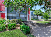 Thumbnail 23 of 42 - a sidewalk in front of a building with trees and bushes