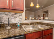 Thumbnail 14 of 28 - A kitchen with a granite countertop and a stone backsplash.