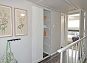 Thumbnail 6 of 35 - A hallway with a white railing and two framed pictures on the wall.