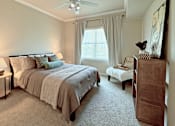 Thumbnail 3 of 26 - A bedroom with a large bed and a small table with a lamp on it.