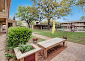 Thumbnail 3 of 17 - A wooden bench sits in the middle of a garden.