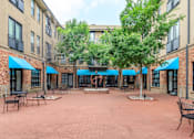 Thumbnail 11 of 34 - A courtyard with tables and chairs surrounded by brick buildings.