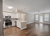 Thumbnail 24 of 40 - an empty kitchen and living room with wood flooring and white cabinets