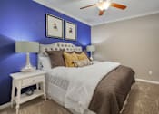 Thumbnail 34 of 40 - a bedroom with a bed and a blue wall and a ceiling fan