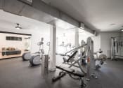 Thumbnail 28 of 54 - a gym with cardio equipment and a living room with a couch