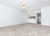 Thumbnail 31 of 43 - an empty living room with a ceiling fan and a kitchen