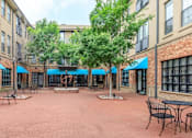Thumbnail 11 of 34 - A courtyard with tables and chairs surrounded by brick buildings.