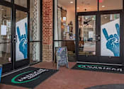 Thumbnail 12 of 34 - The entrance to a building with a glass door and a sign on the floor.