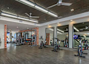 Thumbnail 16 of 34 - A gym with a variety of exercise equipment including treadmills, stationary bikes, and weight machines.