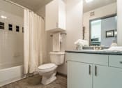 Thumbnail 26 of 34 - A white toilet is in a bathroom with a white shower curtain.